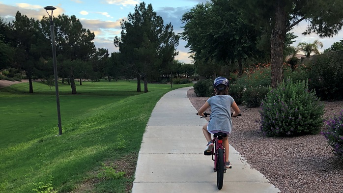 Child biking along a sidewalk in the park