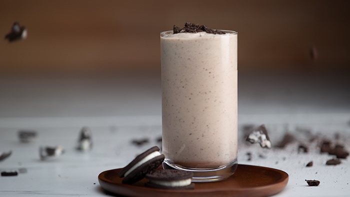 A glass jar full of Cookies & Cream IsaLean Shake topped with cookie crumbles