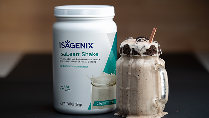A canister of limited-edition Cookies & Cream IsaLean Shake next to an overflowing mason jar of shake