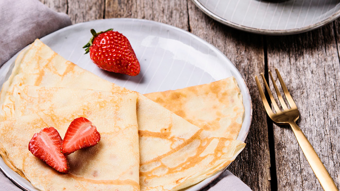 Plate with crepes and strawberries and a fork on the side