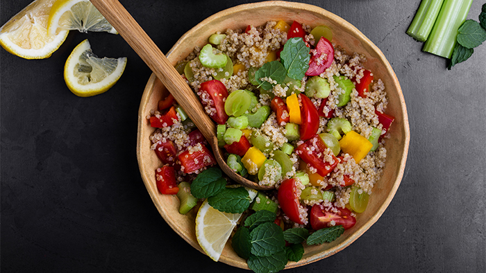 A wooden bowl of quinoa and fresh produce