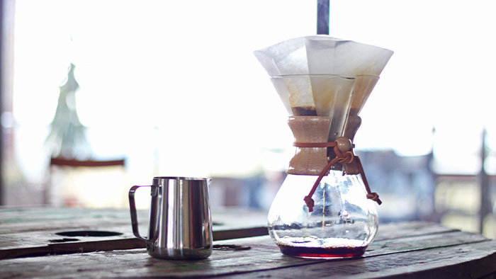 A chemex with a filter and a mug on a table