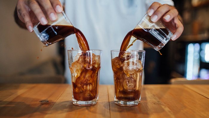 Someone pouring cold brew coffee into two glasses with ice