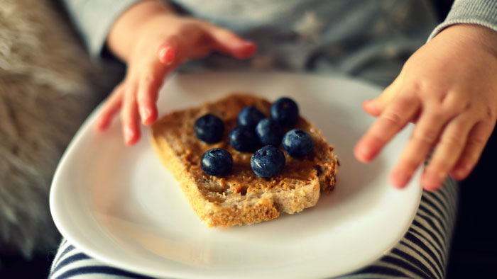 A plate of peanut butter toast with blueberries on top