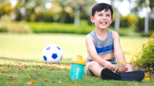 Young boy smiling and enjoying super smoothie after playing soccer
