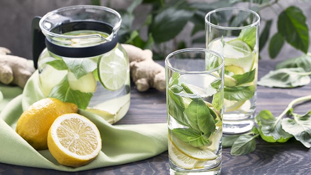 Pitcher of water with lime and mint with cut lemons and glasses of water