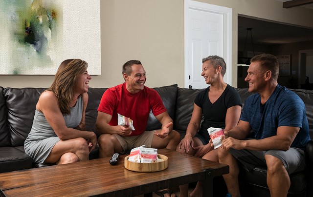 Four people sitting on a couch talking and enjoying Isagenix products