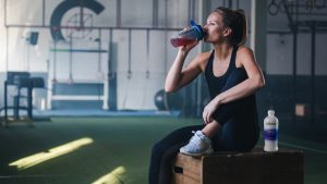 Woman drinking from an Isagenix shaker cup at the gym