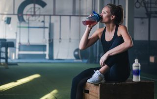 Woman drinking from an Isagenix shaker cup at the gym