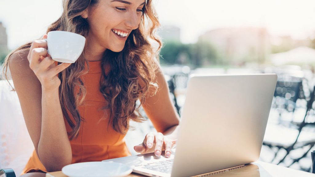 Woman holding a mug and working on a laptop