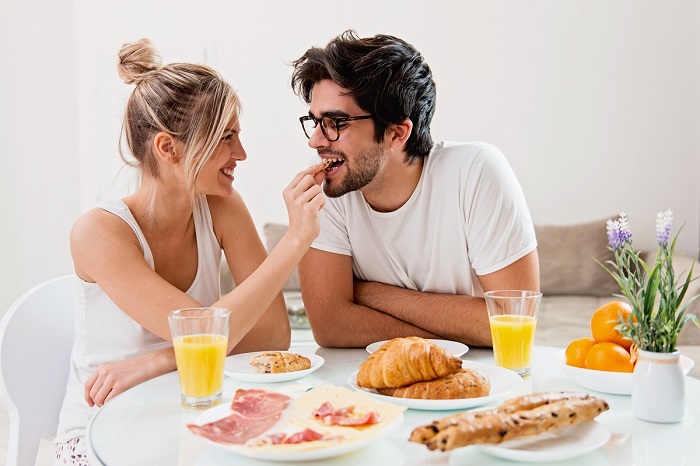 A couple smiles and enjoys breakfast together