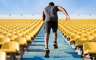 Man running up blue stairs surrounded by bright yellow stadium seats
