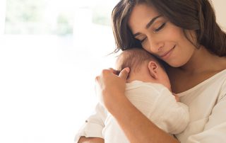 Happy mother cradles her baby to her chest