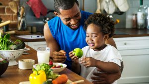 Father and child preparing fresh fruits and veggies in the kitchen