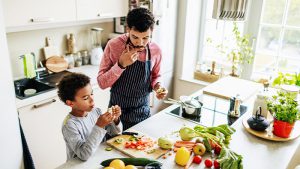 Father and son cutting and eating fruits and vegetables