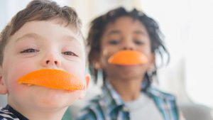 Two boys with orange peels over their mouths