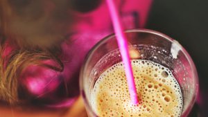 Female holding a glass with a smoothie and a straw in it