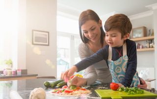 A mother making veggie pizza with her son in the kitchen