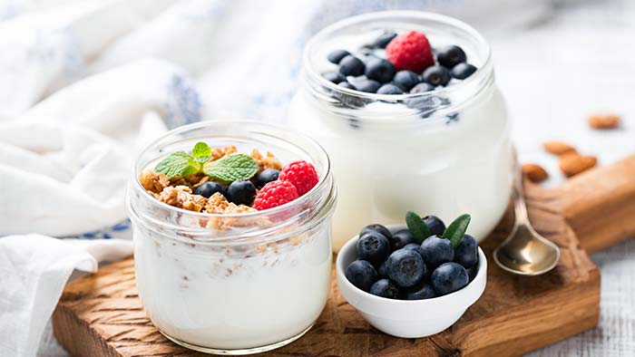Glass jars of yogurt with berries and granola on top