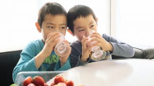 Two boys drinking strawberry smoothies from glasses