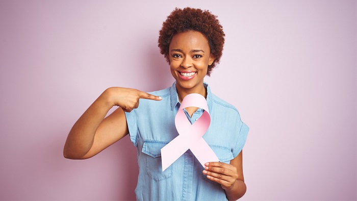 Woman pointing to a breast cancer awareness ribbon she's holding