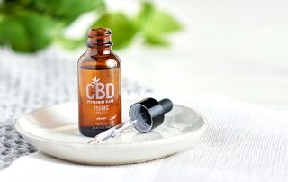Isagenix CBD Peppermint Oil Blend bottle and dropper on a white plate