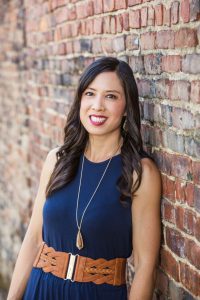 woman in blue blouse by brick wall