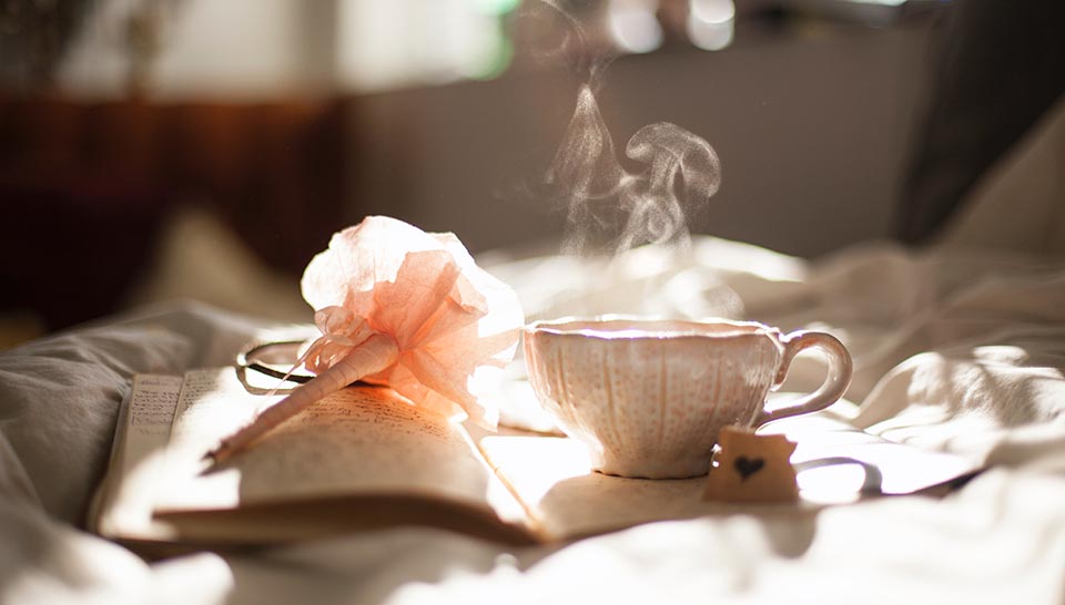 Tea cup with a steaming beverage on a diary