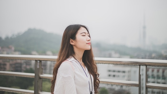 Woman standing outside with her eyes closed