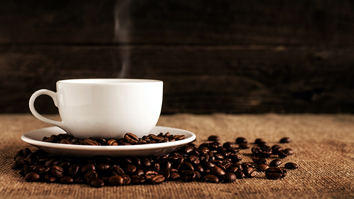 hot cup of coffee resting on coffee beans