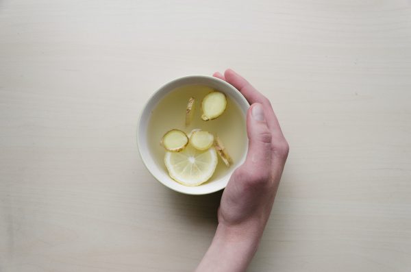 A cup of bone broth with lemon and ginger slices