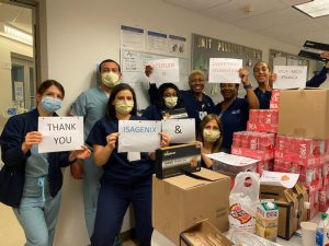 A group of people holding thank-you signs after receiving product donations from Isagenix