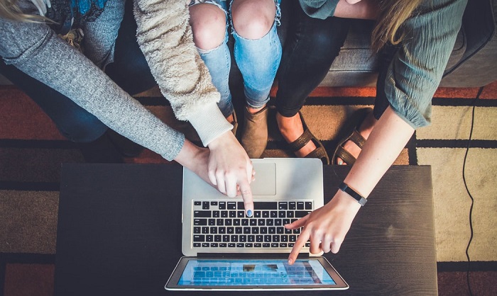 Overhead shot of three young women pointing to a laptop screen