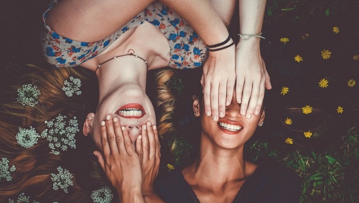 Two women smiling and lying down with flowers in their hair