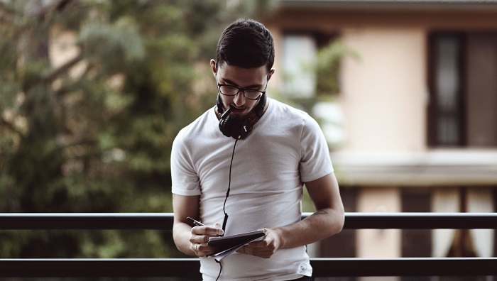 Man with headphones taking notes