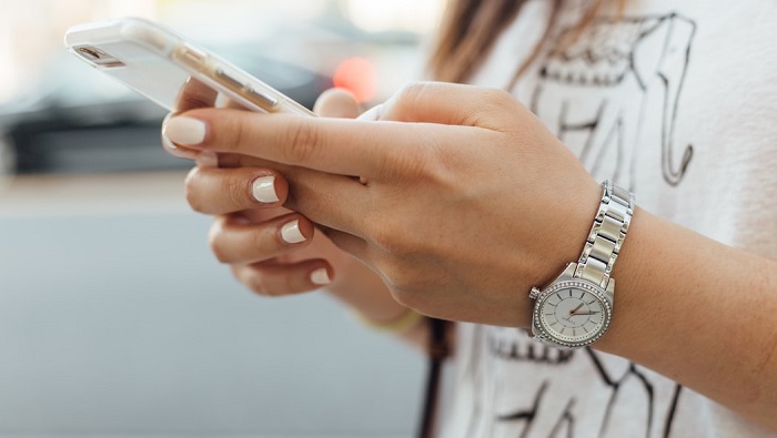 A close-up of hands holding a phone and typing