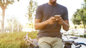 Man holding cellphone while sitting on bike