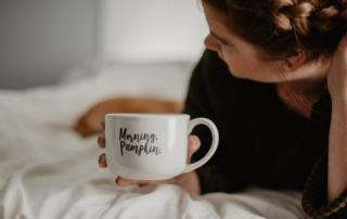 Woman lying in bed with a white coffee mug