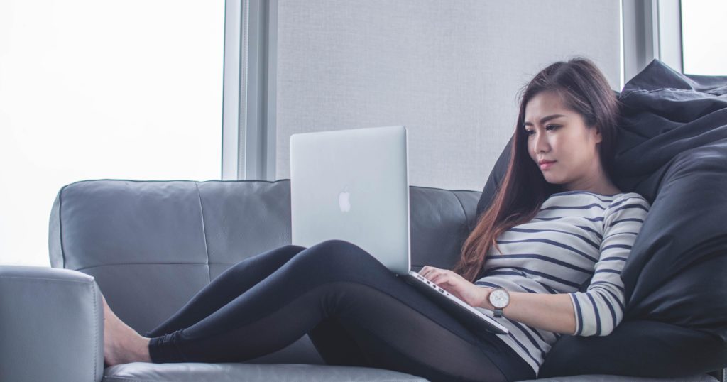 Woman typing on her laptop while on the couch