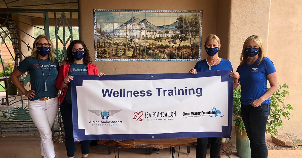 4 women holding a wellness training banner