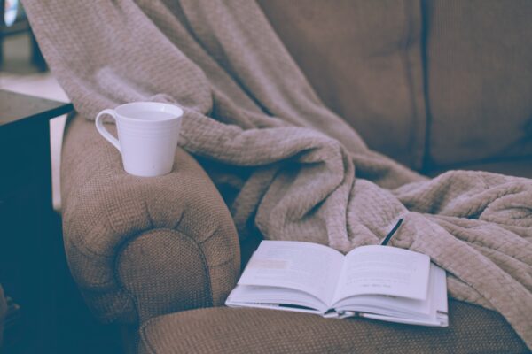 Book, blanket, and coffee mug on brown couch