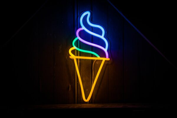 Neon ice cream cone sign against dark background