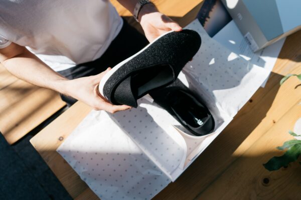 Overhead shot of woman unboxing black slip-on shoes