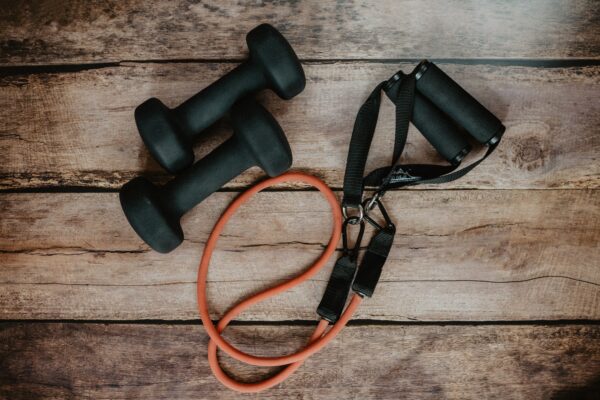 Two dumbbells and a resistance band on a wooden background