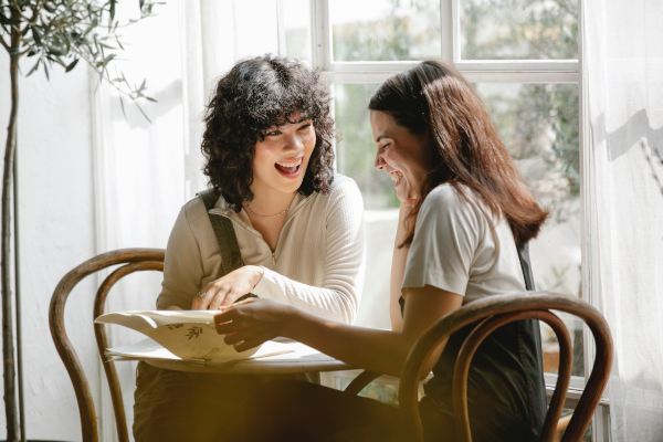 Two friends smiling and talking at a table