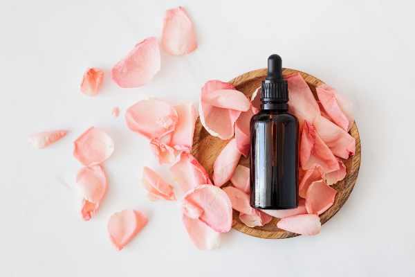Essential oil bottle in a bowl full of pink flower petals